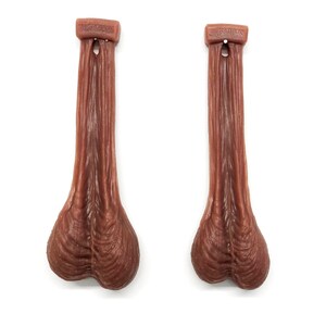 May include: Two brown rubber testicles with the text "HILLSIDE FARMERS" printed on the top of each.