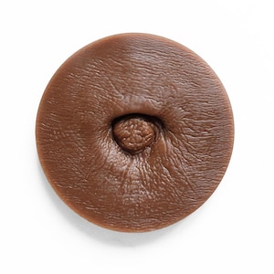 May include: A close-up of a brown, textured, round object with a small, raised, circular detail in the centre.