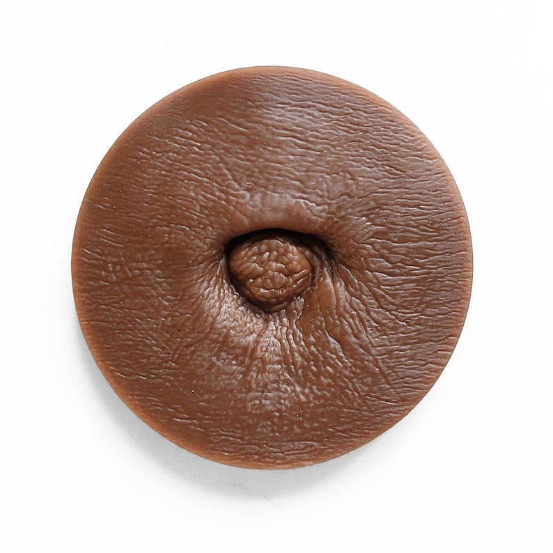 May include: A close-up of a brown, textured, round object with a small, raised, circular detail in the centre.