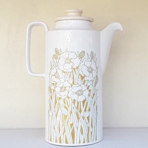 May include: White ceramic coffee pot with a gold floral design. The pot has a lid and a handle.