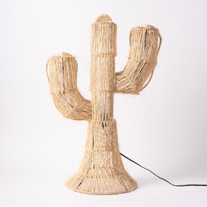 May include: A beige rope cactus lamp with a black cord. The lamp is made of woven rope and has a three-pronged design.