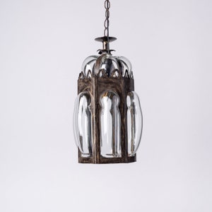 Könnte beinhalten: Eine schwarze Metall- und Glas-Pendelleuchte mit geometrischem Design. Die Leuchte hat eine Kette und hängt von der Decke.