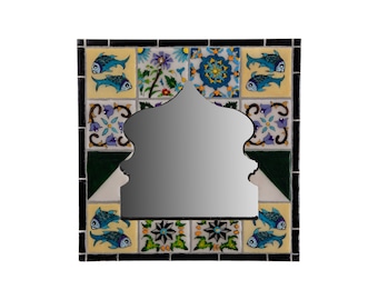 May include: A decorative mirror with a colourful mosaic frame. The frame features blue fish, green and white floral patterns, and yellow and blue geometric designs.