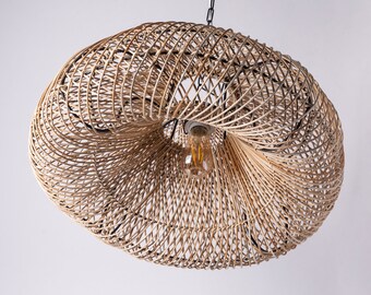Könnte beinhalten: Eine geflochtene Rattan-Pendelleuchte mit einem natürlichen braunen Finish. Die Leuchte hat ein rundes, offenes Design mit einer einzigen Glühbirne in der Mitte.