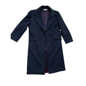 May include: A dark navy blue long-sleeve coat featuring a notched lapel collar, three front buttons, and two flap pockets at the waist. The interior is lined with a deep purple fabric, and a small white brand label is visible at the neck.