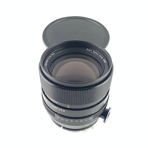 May include: A black Carl Zeiss Jena DDR Sonnar 2/180 lens with a black lens cap.