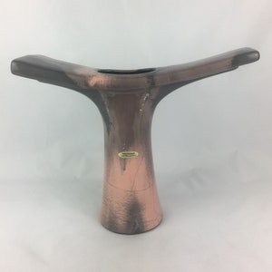 Peut inclure: Un vase en céramique gris et rose avec un design unique en forme de Y. Le vase a une finition texturée et une étiquette qui indique "Orig. Kavanah - Made in Mexico".