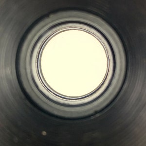 K&ouml;nnte beinhalten: Nahaufnahme des Inneren eines schwarzen Metallrohrs mit einer kreisf&ouml;rmigen &Ouml;ffnung am Ende. Die &Ouml;ffnung ist von einer Reihe konzentrischer Ringe umgeben.