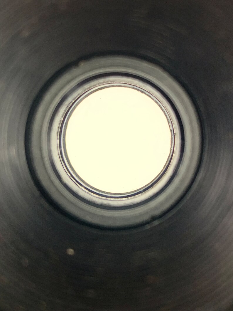 K&ouml;nnte beinhalten: Nahaufnahme des Inneren eines schwarzen Metallrohrs mit einer kreisf&ouml;rmigen &Ouml;ffnung am Ende. Die &Ouml;ffnung ist von einer Reihe konzentrischer Ringe umgeben.