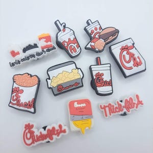 May include: A collection of ten colorful shoe charms featuring fast food themes, including Chick-fil-A branded items like a milkshake, sandwich, waffle fries, and drink cups, along with text charms reading "Lord's calories don't count" and "Chick-fil-A".