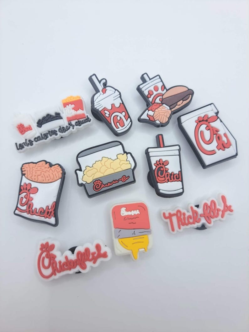 May include: A collection of ten colorful shoe charms featuring fast food themes, including Chick-fil-A branded items like a milkshake, sandwich, waffle fries, and drink cups, along with text charms reading "Lord's calories don't count" and "Chick-fil-A".