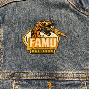 May include: A green, white, and orange embroidered patch with a snake and the text "FAMU Rattlers".