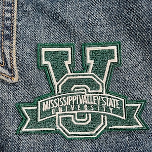 May include: Green and white embroidered patch with the text "Mississippi Valley State University" on a denim jacket.