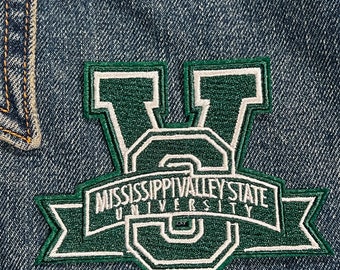 May include: Green and white embroidered patch with the text "Mississippi Valley State University" on a denim jacket.