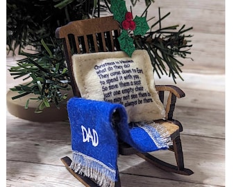 May include: A wooden rocking chair ornament with a white cushion and blue blanket. The cushion has a poem about Christmas in Heaven and the blanket says "DAD".