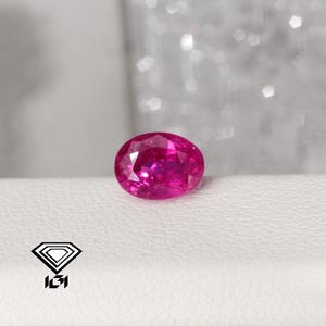 May include: A vibrant pink oval-shaped gemstone with facets.