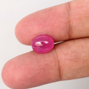 Op de afbeelding: Een levendige roze ovaalvormige robijn edelsteen.