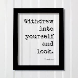 May include: A black rectangular frame containing a white print with the black typewriter-style text: Withdraw into yourself and look. Plotinus. The design features a clean, minimalist aesthetic with bold lettering centered on a plain white background.