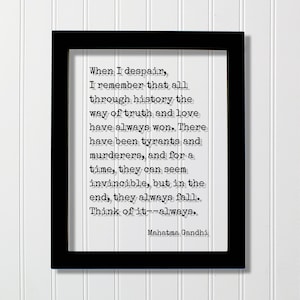 Op de afbeelding: Zwart ingelijst afdruk met een witte achtergrond en een citaat van Mahatma Gandhi in zwart typemachinelettertype. Het citaat luidt: "Wanneer ik wanhoop, herinner ik me dat door de hele geschiedenis de weg van waarheid en liefde altijd heeft gewonnen. Er zijn tirannen en moordenaars geweest, en voor een tijdje kunnen ze onoverwinnelijk lijken, maar uiteindelijk vallen ze altijd. Denk erover na - altijd."