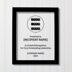 Puede incluir: Un marco rectangular negro que contiene una placa transparente con texto en negro que dice: YOUR LOGO HERE, Presented to [RECIPIENT NAME], In Grateful Recognition For Your Outstanding Leadership, [COMPANY NAME], y el año 2019.