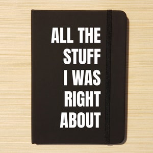 May include: Black notebook with a black elastic band closure. The front cover has white text that reads "ALL THE STUFF I WAS RIGHT ABOUT".