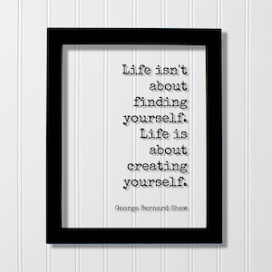 May include: Black framed print with a white background and a quote by George Bernard Shaw: "Life isn't about finding yourself. Life is about creating yourself."