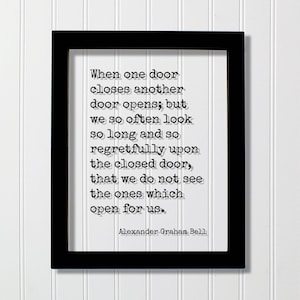 Puede incluir: Un marco rectangular negro que contiene una impresión blanca con la cita: When one door closes another door opens; but we so often look so long and so regretfully upon the closed door, that we do not see the ones which open for us. Alexander Graham Bell.