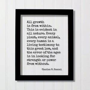 May include: Black framed print with the quote "All growth is from within" by Charles F. Haanel. The text is in a typewriter-style font on a white background. The frame is rectangular and the print is displayed against a white paneled wall.