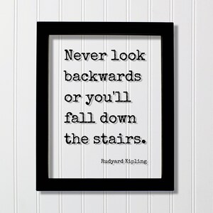 Könnte beinhalten: Ein schwarzer rechteckiger Rahmen mit einem weißen Druck, der den schwarzen Text im Schreibmaschinenstil enthält: Never look backwards or you'll fall down the stairs. Der Name Rudyard Kipling ist in kleinerer schwarzer Schrift unten rechts gedruckt.