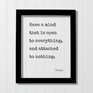 May include: A black rectangular frame containing a white print with the black text: Have a mind that is open to everything, and attached to nothing. The name Tilopa is printed in the bottom right corner in a typewriter-style font.