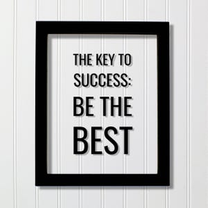 以下が含まれることがあります： 黒い長方形のフォトフレーム。白い背景に黒い文字で「THE KEY TO SUCCESS: BE THE BEST」と書かれたプリントが入っています。フレームはシンプルでクリーンなデザインで、太字のサンセリフ体で引用文が表示されています。