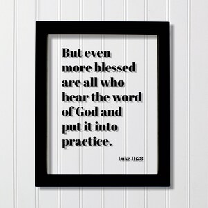 以下が含まれることがあります： 黒い長方形のフレームに、白いプリントと黒いテキスト「But even more blessed are all who hear the word of God and put it into practice. Luke 11:28」が収められています。文字には白い背景に対してはっきりとしたドロップシャドウ効果が施されています。