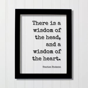 Op de afbeelding: Een zwarte rechthoekige lijst met een witte print met de zwarte tekst in typemachinestijl: There is a wisdom of the head, and a wisdom of the heart. Charles Dickens. Het citaat is gecentreerd in de lijst met een duidelijk leesbaar lettertype.