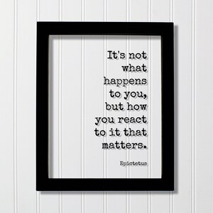 Puede incluir: Un marco rectangular negro que contiene una impresión blanca con el texto negro: It's not what happens to you, but how you react to it that matters. Epictetus. Las letras están en una fuente de estilo máquina de escribir, centradas.