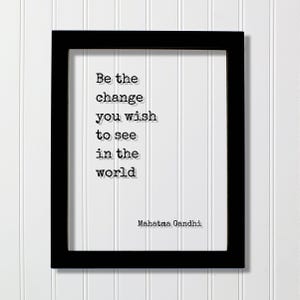 Puede incluir: Un marco rectangular negro que contiene un fondo blanco con el texto negro estilo máquina de escribir: Be the change you wish to see in the world. El nombre Mahatma Gandhi está impreso en la esquina inferior derecha del área blanca.