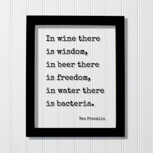 May include: Black framed print with a white background and black text that reads "In wine there is wisdom, in beer there is freedom, in water there is bacteria." The text is attributed to "Ben Franklin".