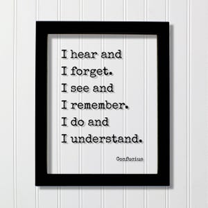 Op de afbeelding: Een zwarte rechthoekige lijst met een witte print met de zwarte tekst in typemachinestijl: I hear and I forget. I see and I remember. I do and I understand. De naam Confucius staat in de rechterbenedenhoek van het witte papier.