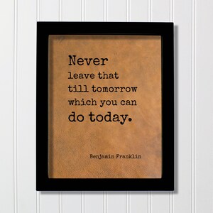 May include: A black rectangular frame containing a tan, textured background with the black printed text: Never leave that till tomorrow which you can do today. Benjamin Franklin. The quote is centered in a typewriter-style font on the surface.