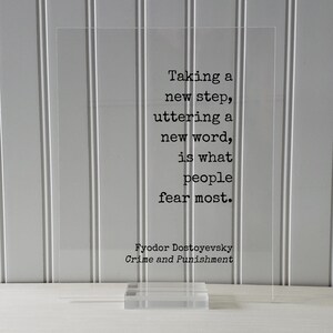 May include: A white acrylic block with a black quote from Fyodor Dostoevsky's Crime and Punishment: "Taking a new step, uttering a new word, is what people fear most."