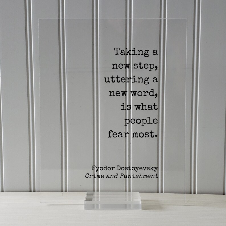 May include: A white acrylic block with a black quote from Fyodor Dostoevsky's Crime and Punishment: "Taking a new step, uttering a new word, is what people fear most."