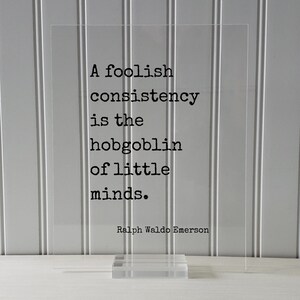 May include: A clear acrylic sign with a black quote that reads "A foolish consistency is the hobgoblin of little minds."  The quote is attributed to Ralph Waldo Emerson.