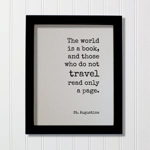 Könnte beinhalten: Ein schwarzer rechteckiger Rahmen mit einem weißen Druck und dem schwarzen Text: The world is a book, and those who do not travel read only a page. St. Augustine. Die Schriftart ist im Stil einer Schreibmaschine gehalten.