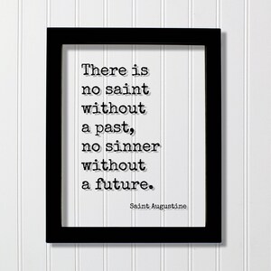 May include: A black rectangular frame containing a white print with the black typewriter-style text: There is no saint without a past, no sinner without a future. Saint Augustine. The lettering features a subtle drop shadow effect on the white background.