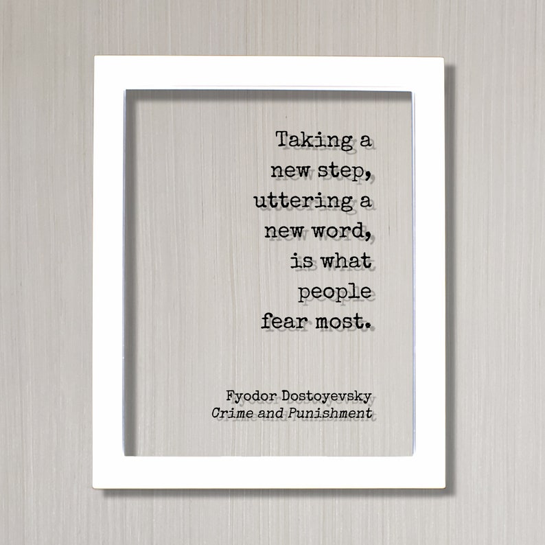 May include: A white framed print featuring a black and white quote from Fyodor Dostoevsky's Crime and Punishment. The quote reads: "Taking a new step, uttering a new word, is what people fear most."