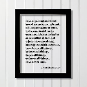 May include: Black framed print with a white background and black text. The text is a quote from the Bible, 1 Corinthians 13:4-8, about love. The quote reads: "Love is patient and kind: love does not envy or boast; it is not arrogant or rude. It does not insist on its own way; it is not irritable or resentful; it does not rejoice at wrongdoing, but rejoices with the truth. Love bears all things, believes all things, hopes all things, endures all things. Love never ends."
