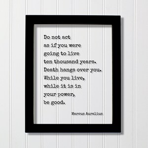 Op de afbeelding: Een zwarte rechthoekige lijst met een witte print met de zwarte tekst: Do not act as if you were going to live ten thousand years. Death hangs over you. While you live, while it is in your power, be good. Marcus Aurelius.