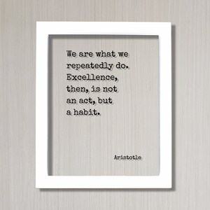 Op de afbeelding: Een wit ingelijst print met een zwart-wit citaat van Aristoteles: "We zijn wat we herhaaldelijk doen. Excellentie is dan geen daad, maar een gewoonte."