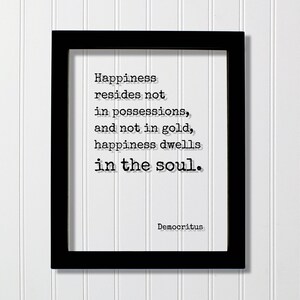 Op de afbeelding: Een zwarte rechthoekige lijst met een witte print met de zwarte tekst in typemachinestijl: Happiness resides not in possessions, and not in gold, happiness dwells in the soul. De naam Democritus staat in de rechterbenedenhoek.