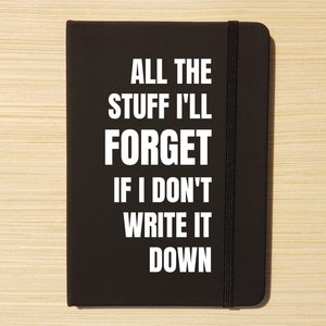 Può includere: Un taccuino nero con una chiusura elastica nera. La copertina anteriore ha un testo bianco che recita "All the stuff I'll forget if I don't write it down."