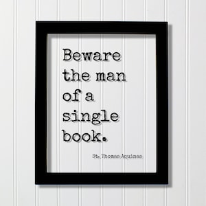 Puede incluir: Impresión enmarcada en negro con la cita "Beware the man of a single book." en fuente de máquina de escribir. El autor, St. Thomas Aquinas, está acreditado en la parte inferior. La impresión se muestra sobre un fondo blanco con paneles verticales.
